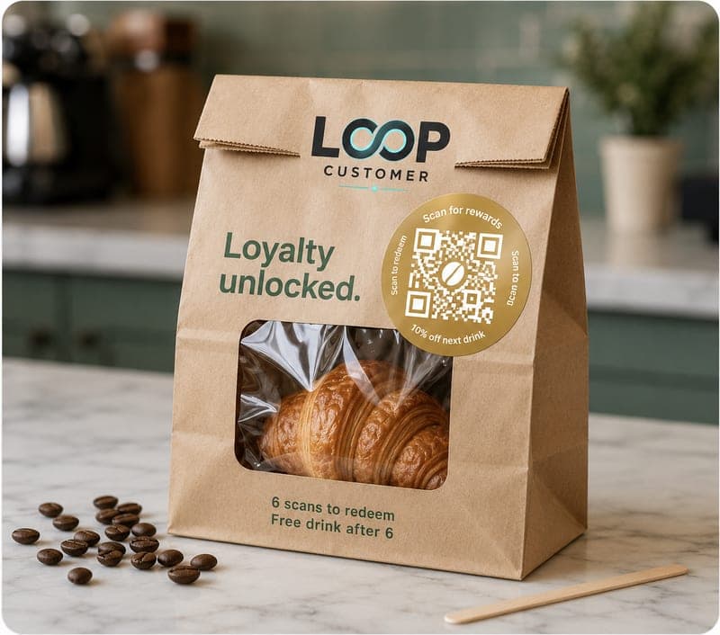A kraft bag and croissant with a Loop sticker reading loyalty unlocked, six scans to redeem.